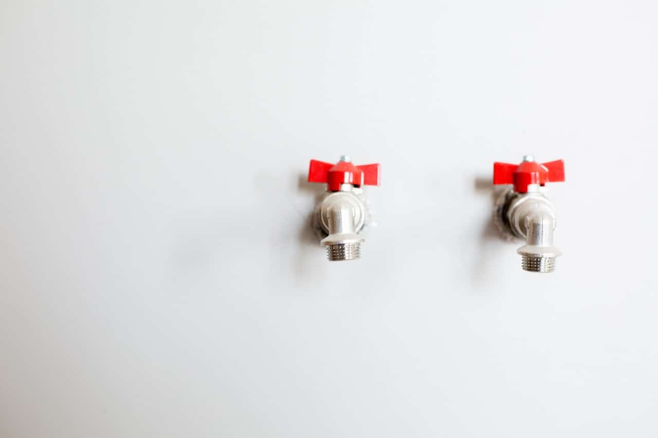 faucets on wall with red handles plumbing