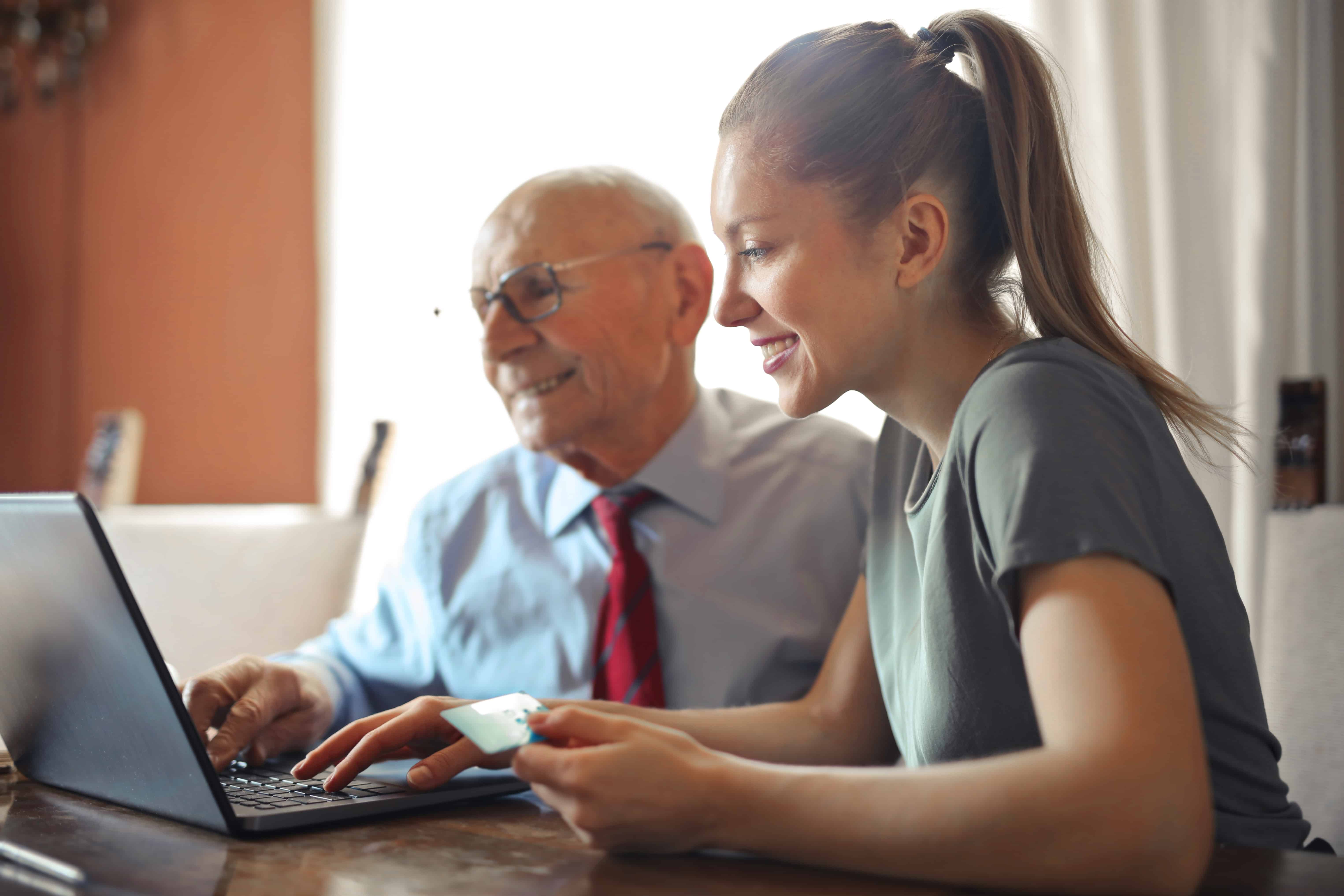 young woman helping senior man on the computer