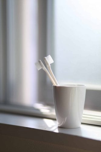 tooth brushes in cup on window sill