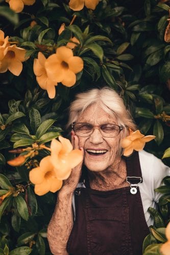 Smiling elderly woman with yellow flowers happiness
